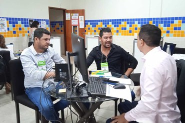 Três pessoas sentadas ao redor de uma mesa conversando