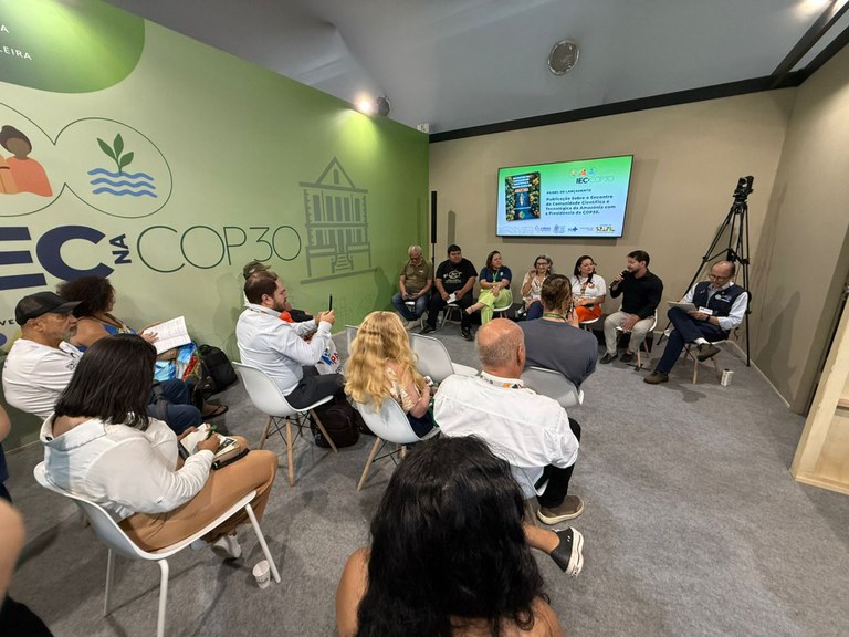 Pessoas sentadas participando do painel no estande do Instituto Evandro Chagas