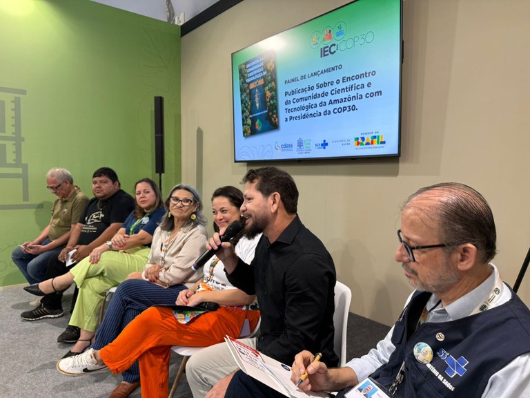 8 pessoas sentadas conversando sobre o painel