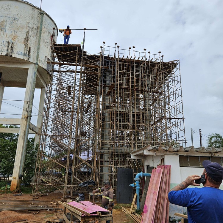 Operário em canteiro de obras focado em estrutura de andaimes de madeira e metal.