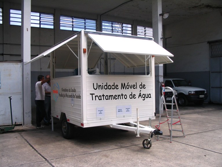 Unidade móvel de tratamento de água da Funasa estacionada em área coberta, equipada para ações emergenciais e apoio a comunidades.