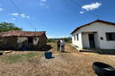 Dois homens posam entre uma casa de taipa antiga e uma casa de alvenaria nova, em terreno de terra- Foto_ Suest-PB_Funasa.jpeg
