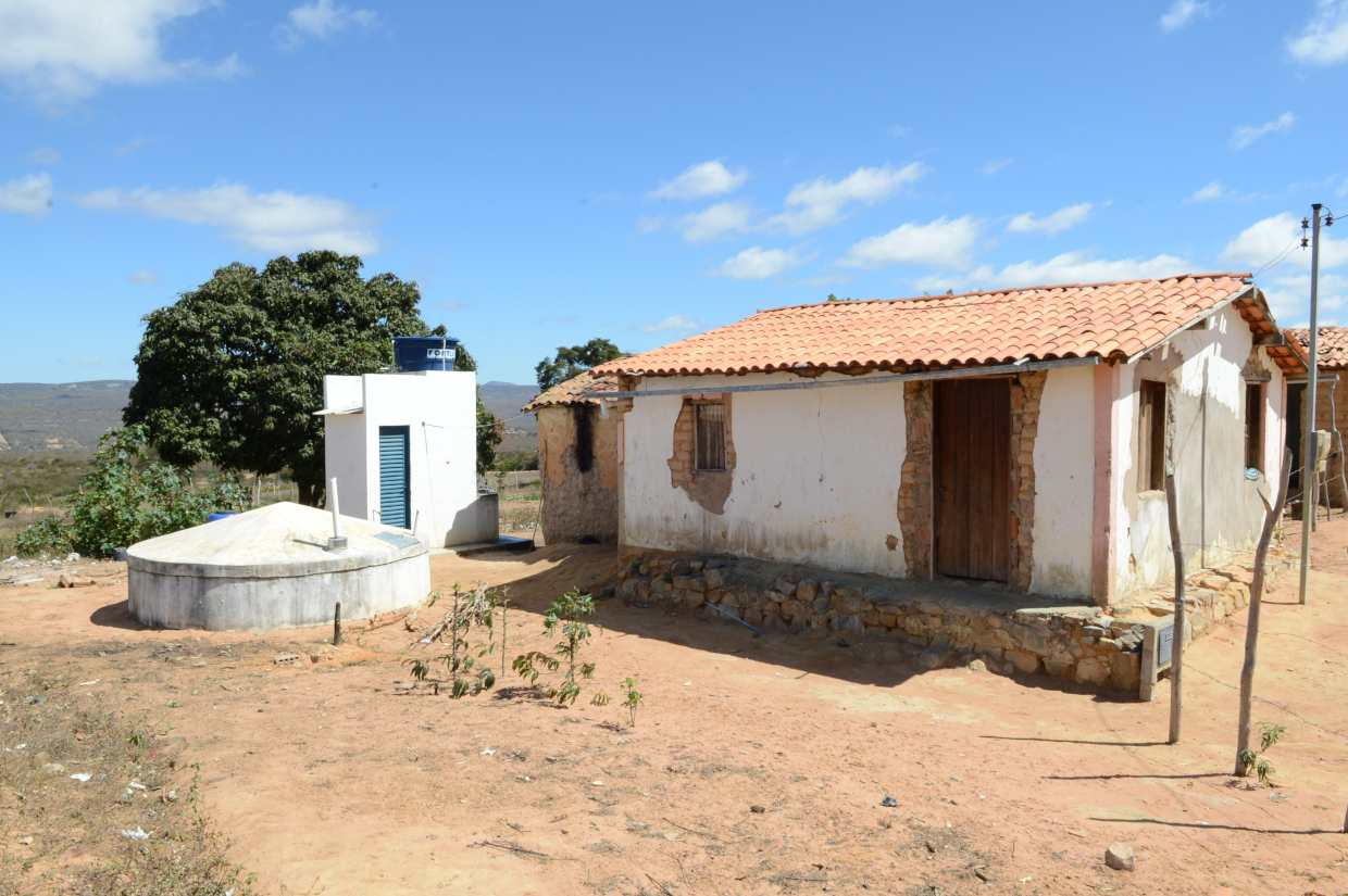 Casa simples contendo uma cisterna fora e um banheiro.