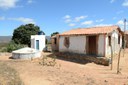 Casa simples contendo uma cisterna fora e um banheiro.