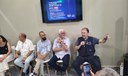 Painel com cinco homens sentados; um deles fala ao microfone. Ao fundo, tela exibe programação do estande CBHSF na COP 30.