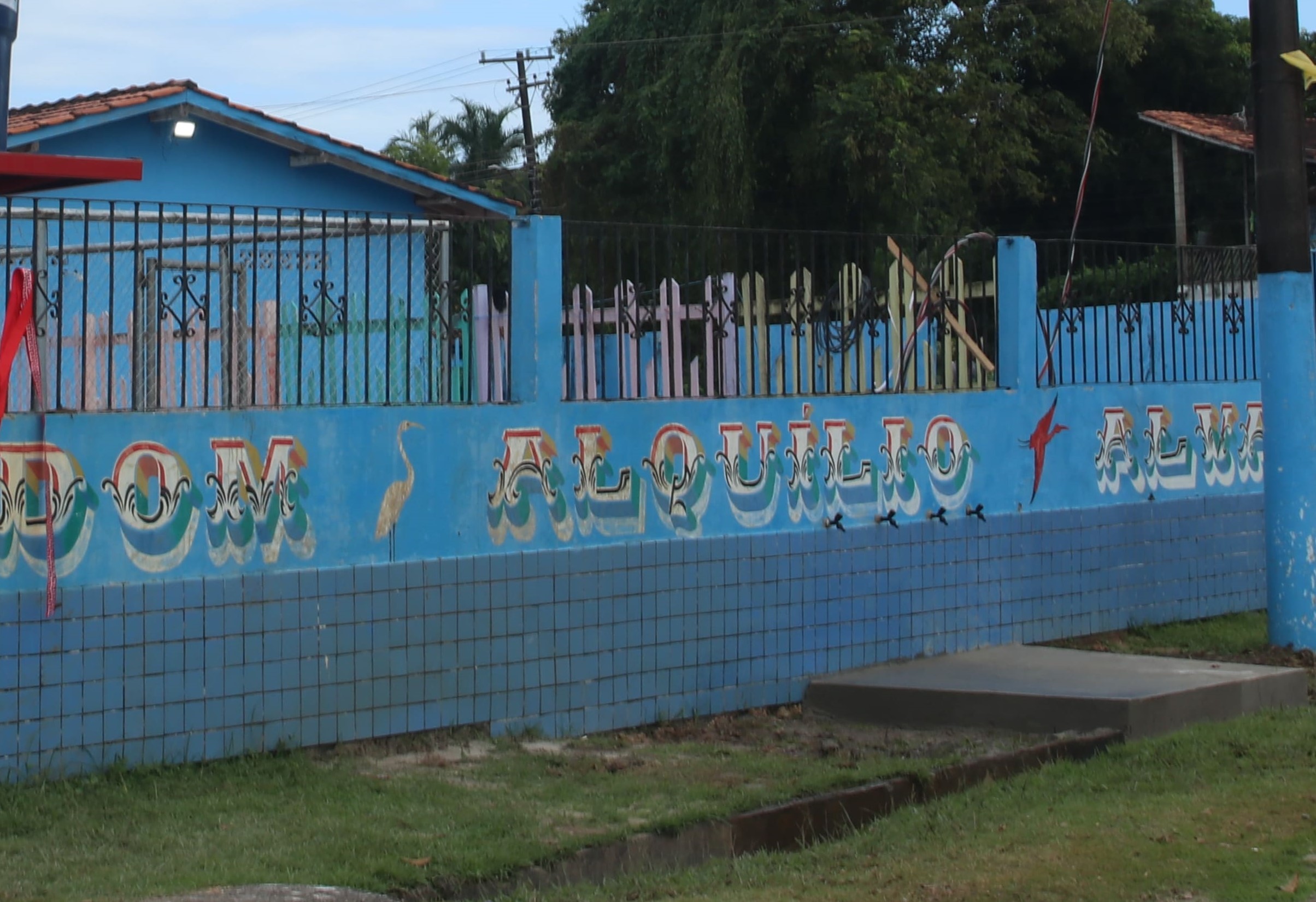 Torneiras na área externa da escola instaladas no muro azul.