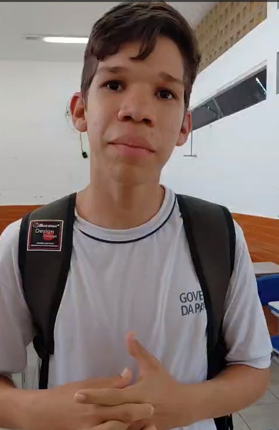 Retrato de um jovem de uniforme branco e mochila preta.