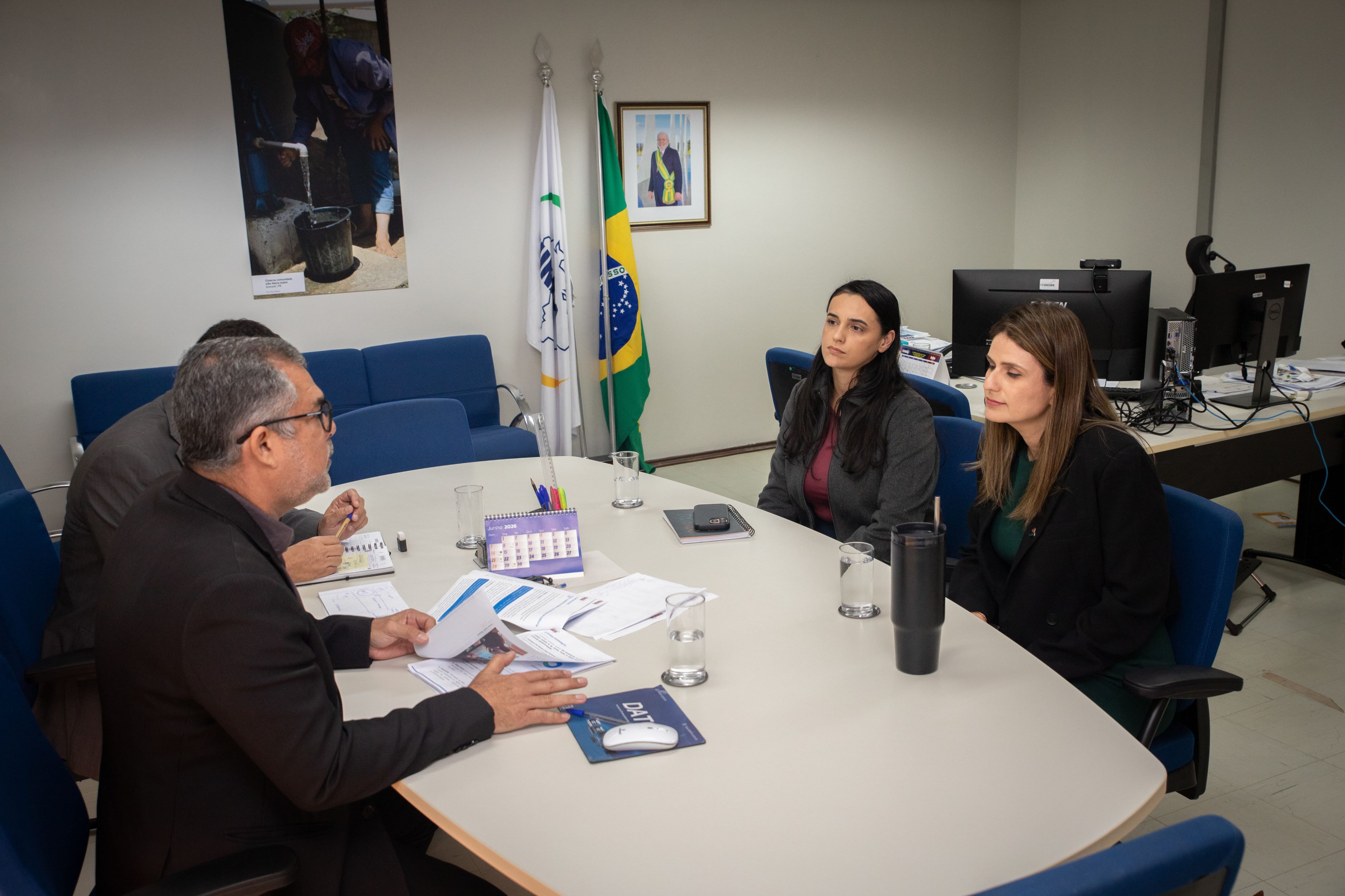 Quatro profissionais debatem documentos ao redor de uma mesa em um escritório.