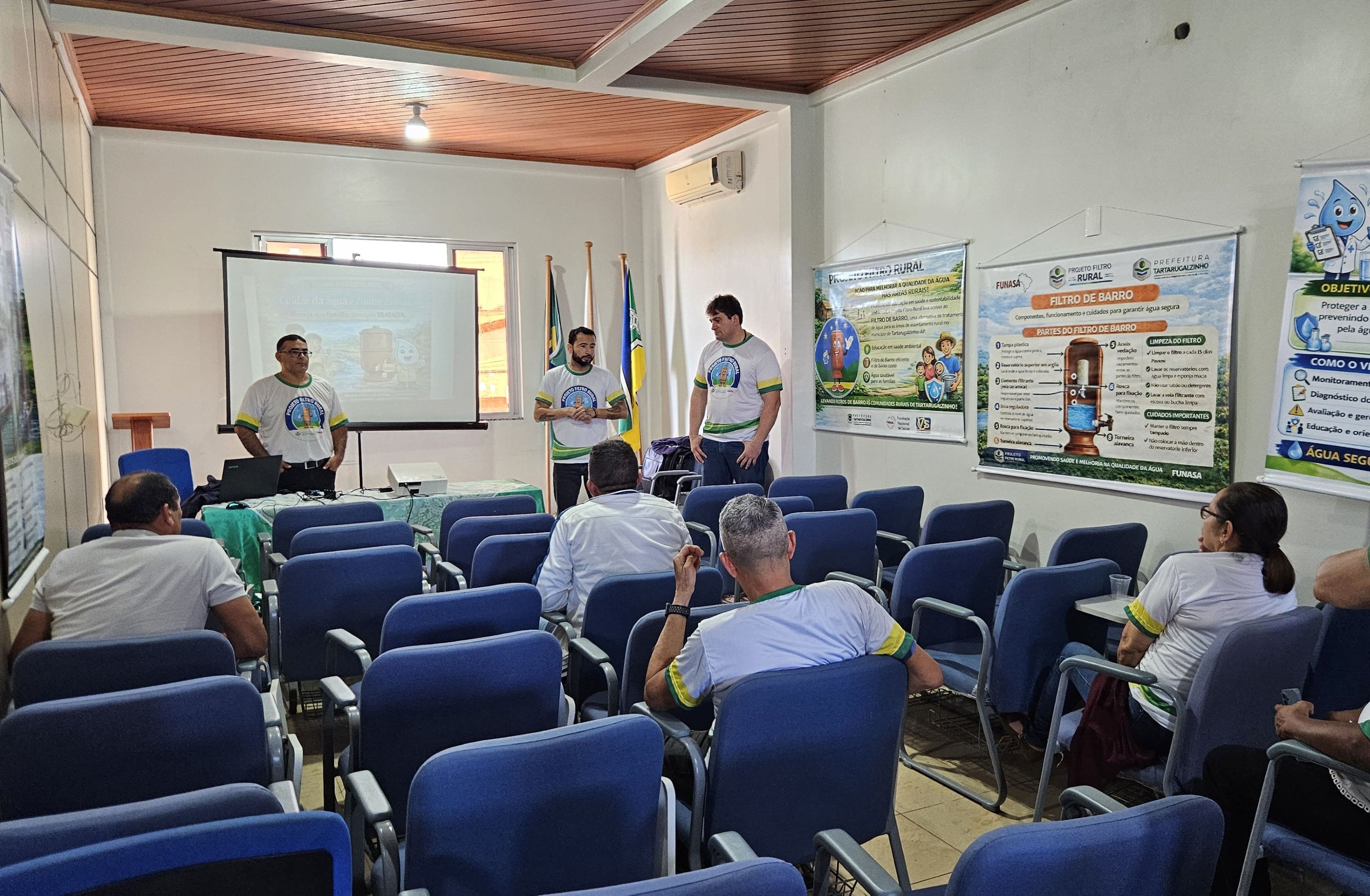 Palestrantes diante de público em auditório com cartazes do Projeto Filtro Rural nas paredes.