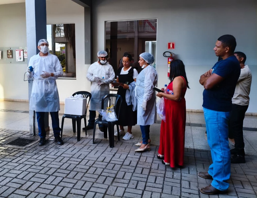 Homem de jaleco orienta grupo de pessoas em treinamento ao ar livre sobre qualidade da água.