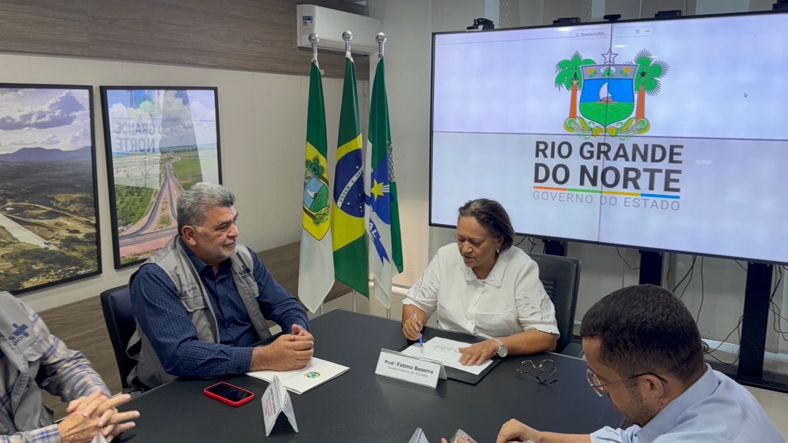 Lenildo Morais e Fátima Bezerra sentados à mesa, conversando sobre projetos de saneamento.