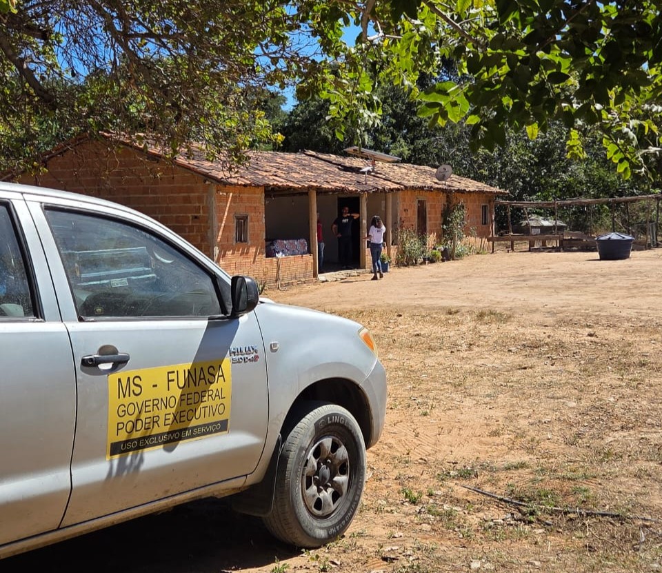 Carro cinza em frente a uma casa de interior feita de tijolos.