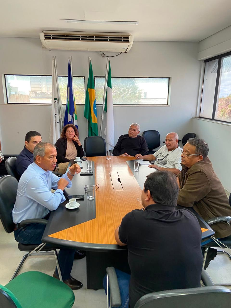 Outro ângulo Pessoas reunidas em torno de uma grande mesa de madeira conversam em uma sala.