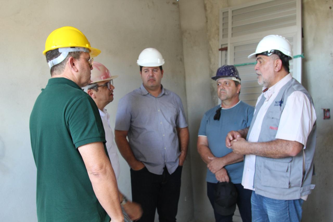 Lenildo Morais e representantes do Cisco conversam com capacetes de proteção em obra do laboratório.