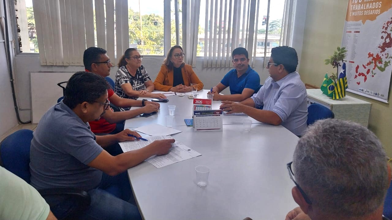 Pessoas reunidas ao redor de uma mesa de escritório conversando durante reunião.