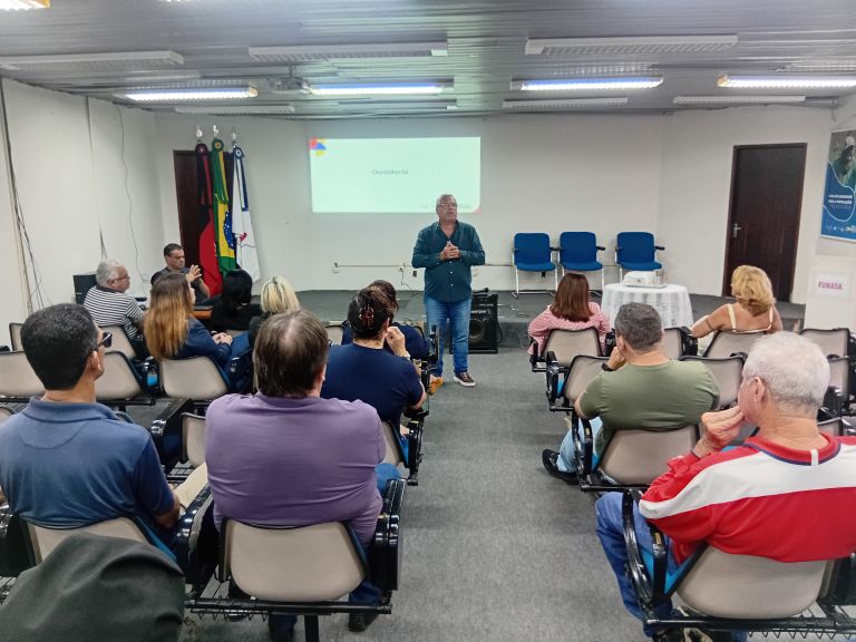 Palestrante fala para auditório com pessoas sentadas; ao fundo, projeção com o texto 'Ouvidoria'.