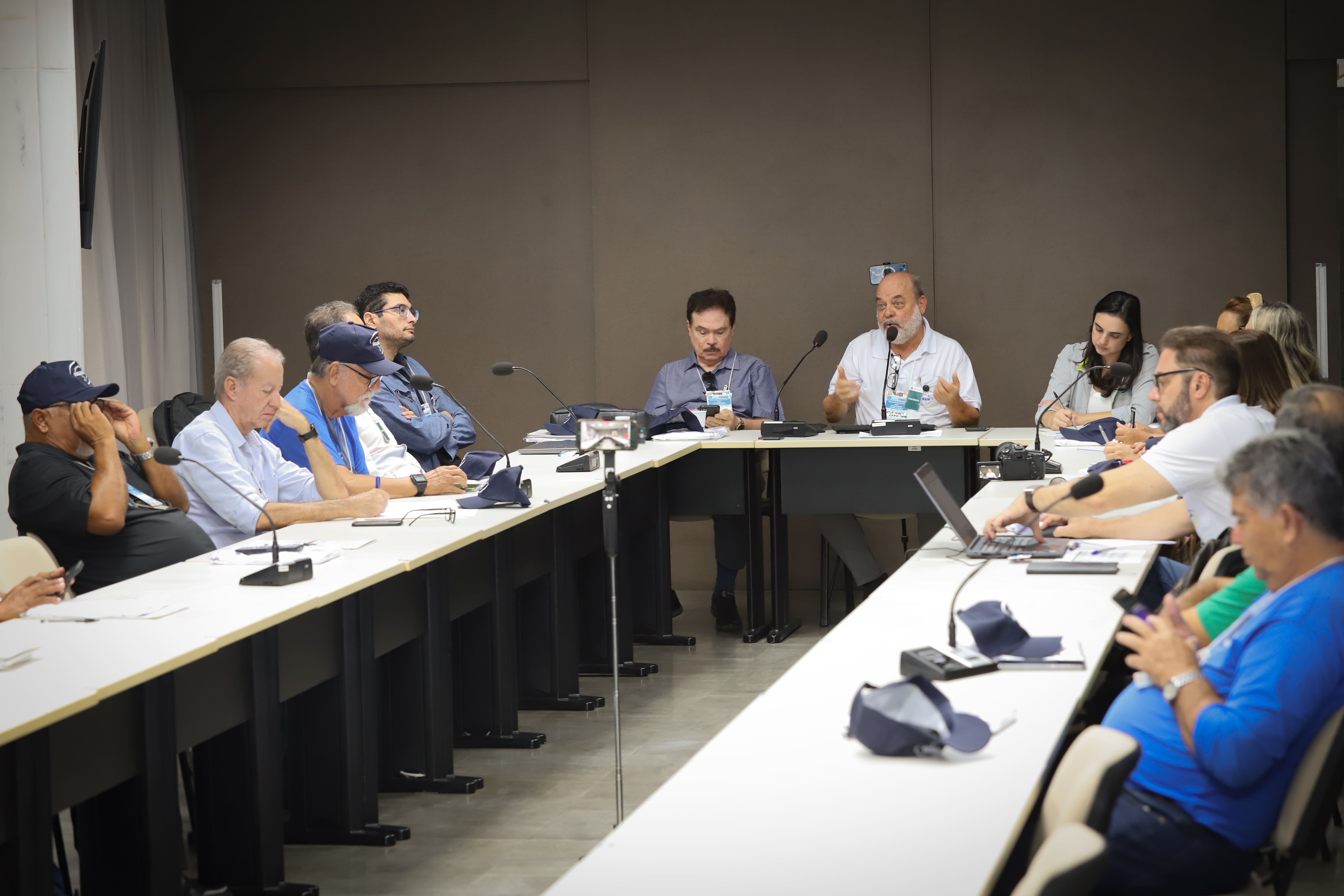 Artur Moret fala ao microfone para equipe da Funasa em mesa de reunião em formato de U.