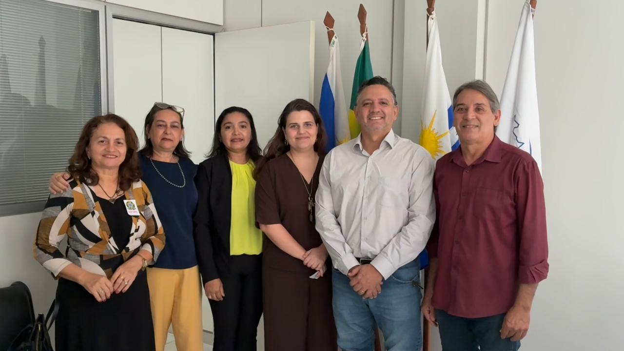 Seis pessoas de frente, 4 mulheres e 2 homens, posando para foto em fundo branco.