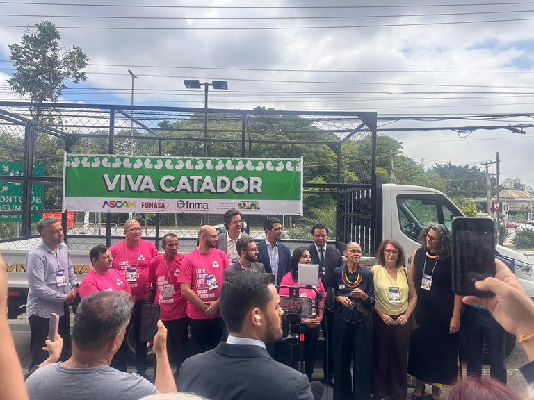 Autoridades e catadores participam da entrega de caminhão do programa Viva Catador, com registro por celulares.