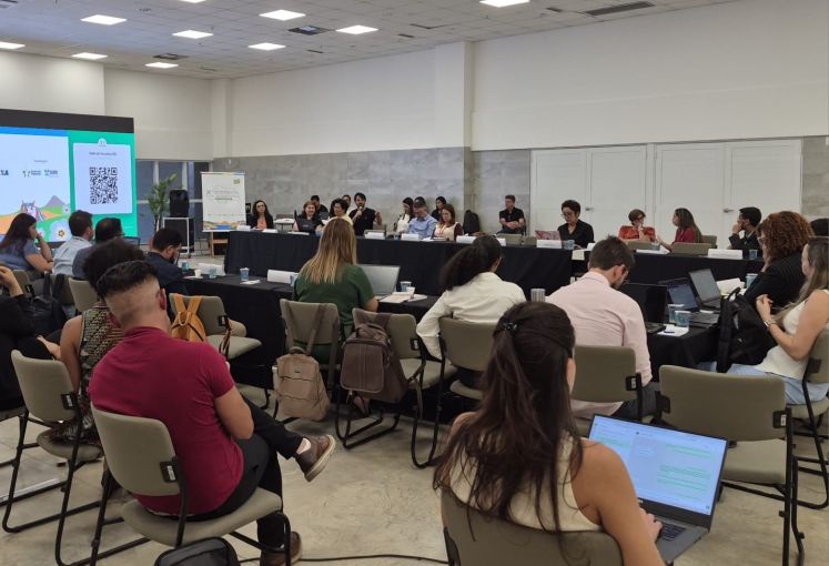 Ampla sala de reuniões com diversos participantes sentados em mesas com notebooks durante o Fórum da Rede de Parcerias.