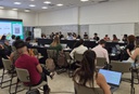 Ampla sala de reuniões com diversos participantes sentados em mesas com notebooks durante o Fórum da Rede de Parcerias.