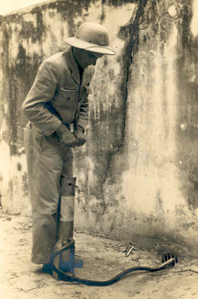 Agente de saúde com chapéu colonial operando bomba manual com mangueira em ralo.