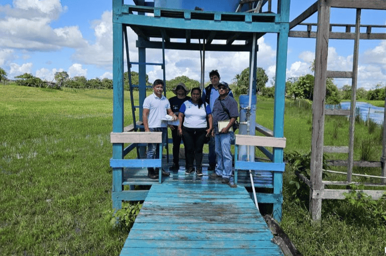 Cinco técnicos posam em frente ao sistema de tratamento de água Salta-Z, montado sobre uma plataforma de madeira azul em área rural.