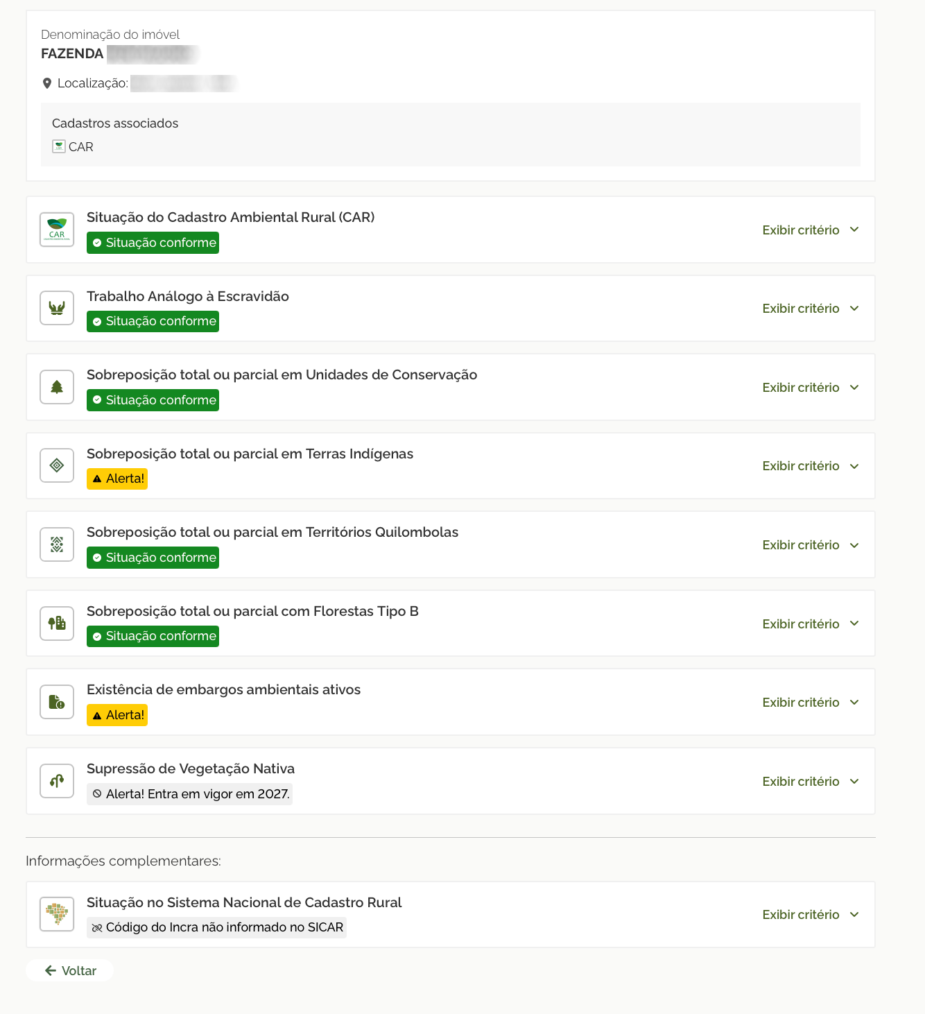 A imagem mostra uma tela de verificação de conformidade de um imóvel rural, com o nome e a localização anonimizados. No topo, aparece a identificação do imóvel, com cadastro associado ao CAR. Abaixo, há uma lista de critérios avaliados, cada um apresentado em um cartão com ícone, título, status e a opção “Exibir critério”. A maioria dos itens aparece como “Situação conforme”, incluindo a situação do Cadastro Ambiental Rural, trabalho análogo à escravidão, sobreposição com unidades de conservação, territórios quilombolas e florestas tipo B. Dois itens aparecem com alerta: sobreposição total ou parcial em Terras Indígenas e existência de embargos ambientais ativos. Há ainda o item “Supressão de Vegetação Nativa”, marcado com aviso de que o alerta entra em vigor em 2027. Na parte inferior, em “Informações complementares”, aparece a situação no Sistema Nacional de Cadastro Rural, indicando que o código do Incra não foi informado no SICAR, além de um botão para voltar.