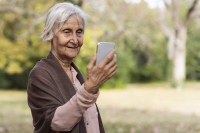 Mulher mais Velha Sorridente Segurando Smartphone e ao Ar Livre