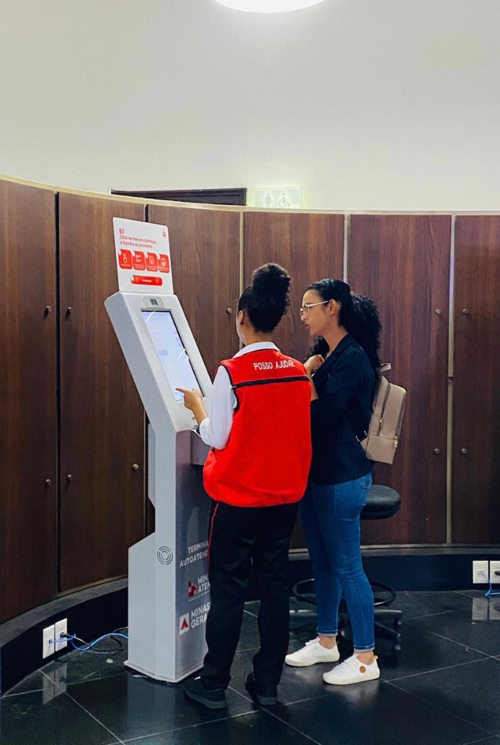 Atendentes da UAI de Minas Gerais orientando cidadãos em guichês individuais, com ambiente movimentado e estrutura para atendimento presencial.