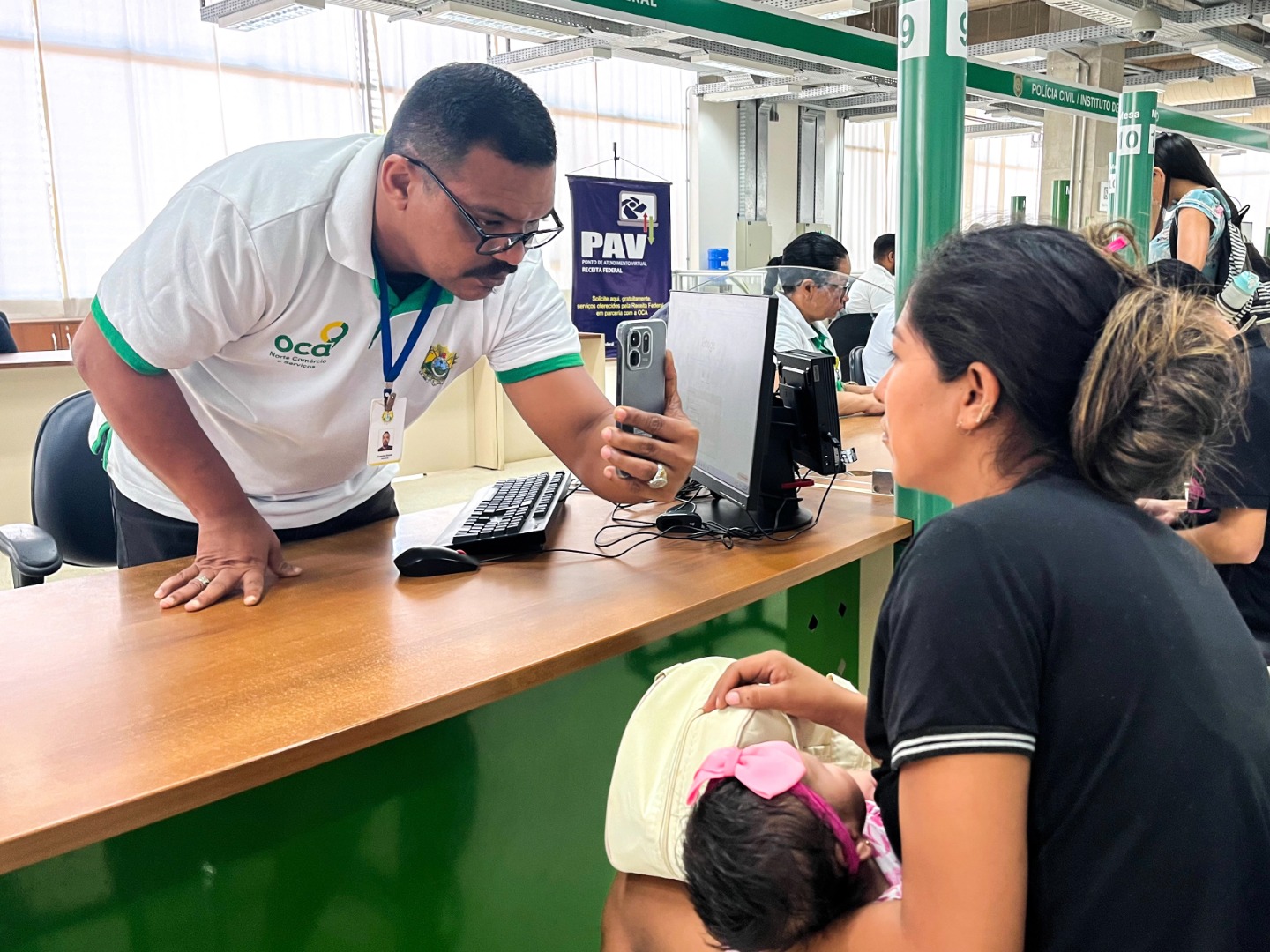 Atendimento na unidade OCA do Acre, com servidores orientando pessoas no local e cidadãos aguardando atendimento.