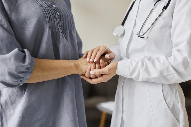 medica-do-centro-de-recuperacao-covid-segurando-as-maos-de-uma-paciente-mais-velha.jpg