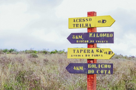 Sinalização indica rotas e destinos ao longo dos Caminhos do Pampa, incluindo comunidades e pontos locais como o Bolicho do Cota, integrando o território à experiência da trilha. Foto: Daniel Gobbi