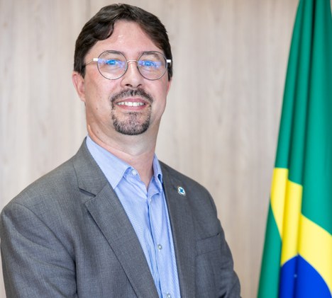Imagem de homem branco sorrindo com a bandeira do Brasil ao fundo