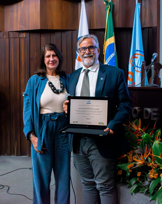 Diretor do IEN/CNEN recebendo a placa em homenagem do Instituto de Pesquisas Energéticas e Nucleares (IPEN), entregue pelas mãos da Coordenadora de Administração e Infraestrutura, Kátia Cristina Iunes Minasian Santos. Foto: Gledson Júnior