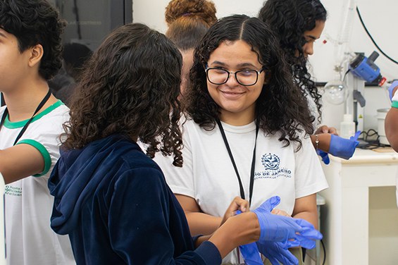 Estudantes usando luvas de proteção durante a parte prática da oficina no Laboratório de Nanorradiofármacos.