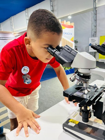 Menino usando microscópio no estande da CNEN na SBPC