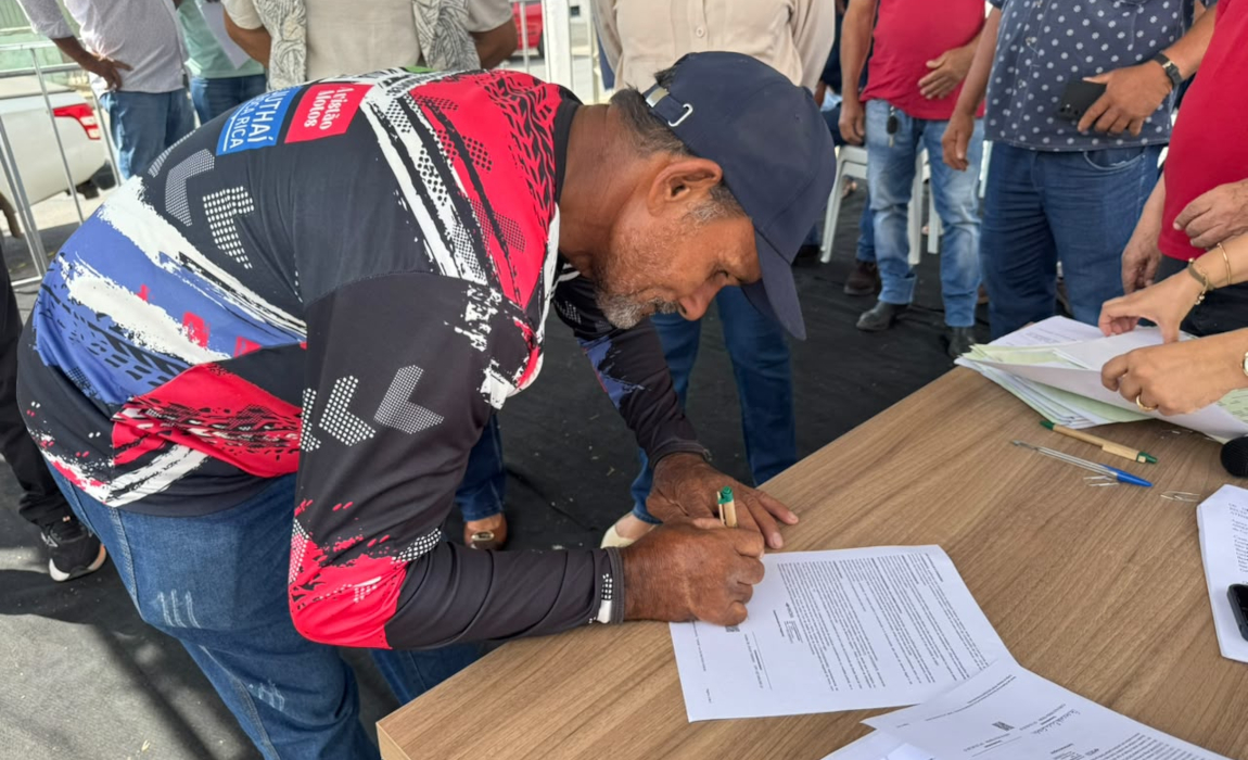 Um homem de boné assinando um documento.