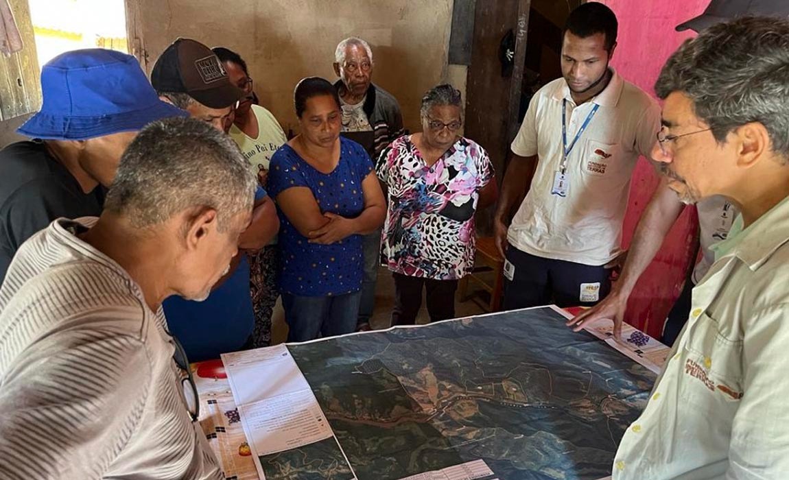 Homens e mulheres olhando um mapa aberto em cima de uma mesa..