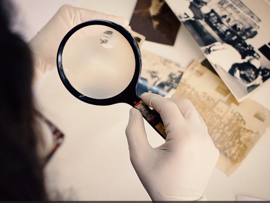 Pesquisador com lupa olha documentos do arquivo Augusto Ruschi