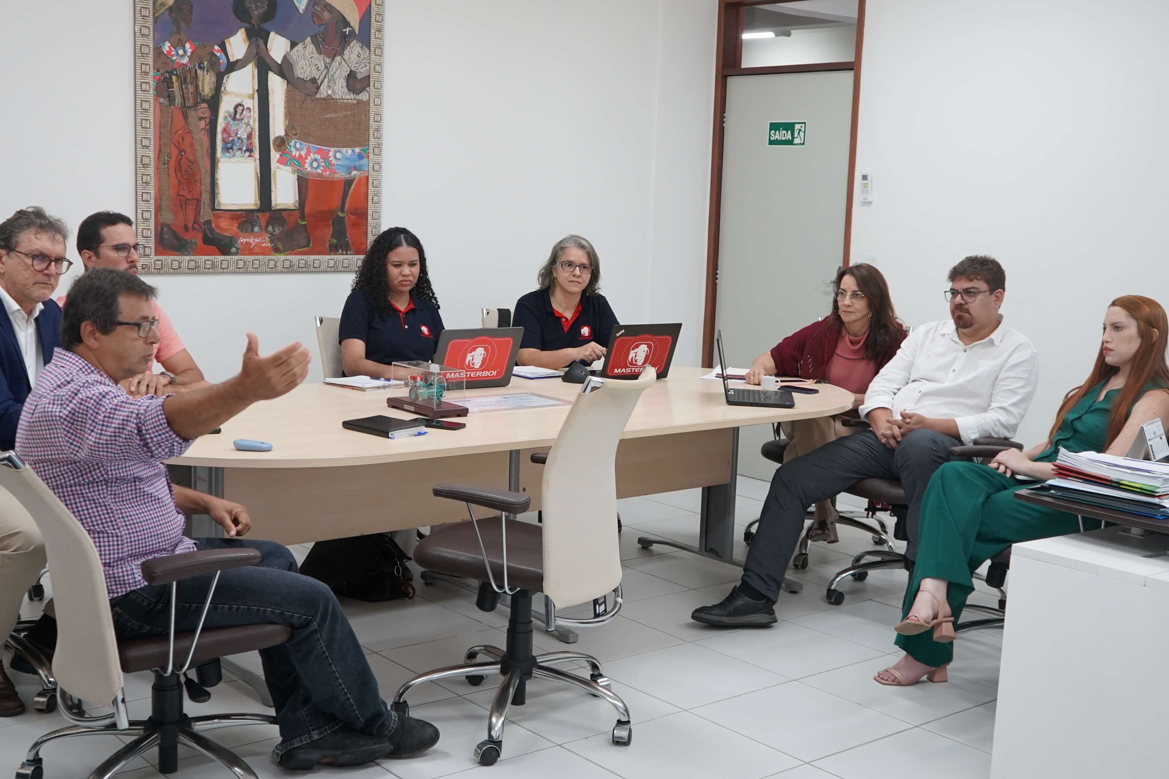 Ao redor de mesa de reuniões, pessoas discutem parceria