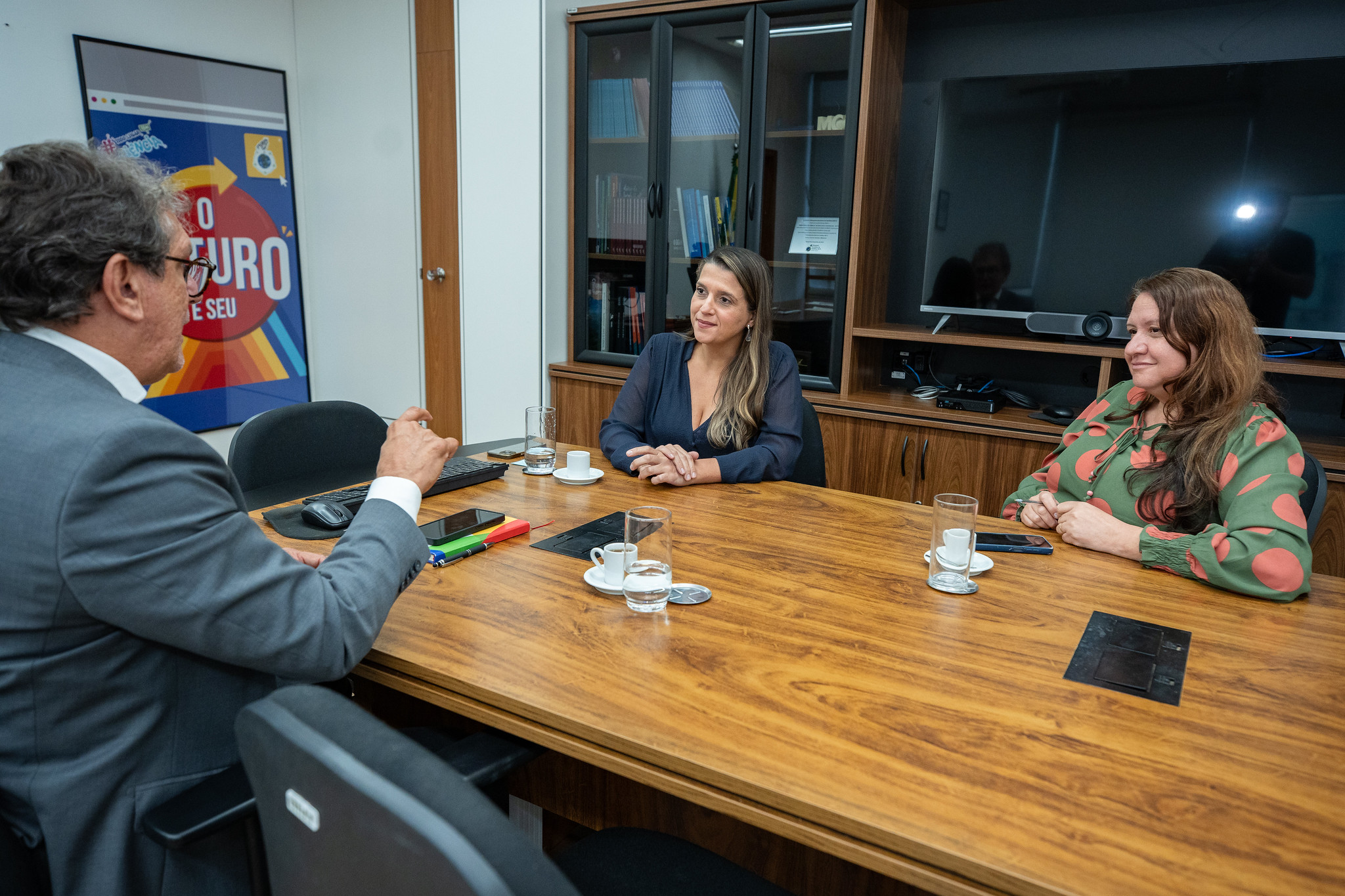 Em sala de reunião, diretor do INSA dialoga com mais duas mulheres.