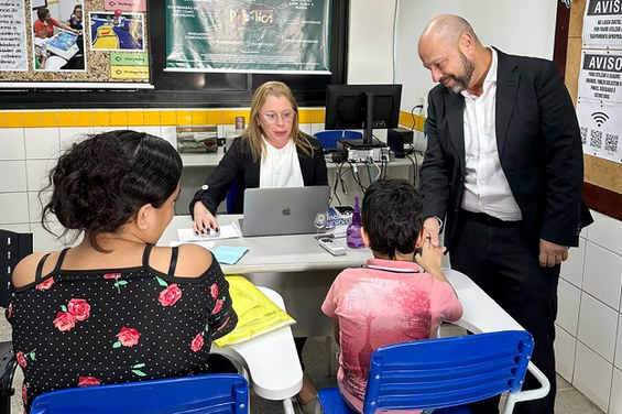 residente do INSS cumprimenta criança e mãe que recebem atendimento no mutirão do Inclusão Nordeste, em Natal (RN). Foto: Ana Paula Ergang/ Ascom INSS.