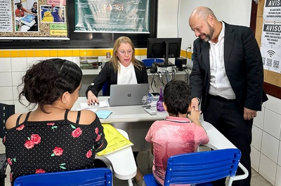 residente do INSS cumprimenta criança e mãe que recebem atendimento no mutirão do Inclusão Nordeste, em Natal (RN). Foto: Ana Paula Ergang/ Ascom INSS.