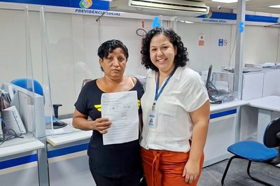 Descrição da imagem: Servidora do INSS entrega carta de benefício para a segurada Lucrécia Flores, na Agência da Previdência Social, em Jacarepaguá / RJ, durante atendimento extraordinário. Foto: Lizandra dos Santos.