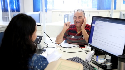 O segurado do INSS, Edinei Gomes Pereira, recebendo atendimento no guichê da APS em Planaltina  DF.