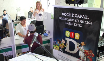 Pessoas sendo atendidas a esquerda e banner/cartaz escrito você é capaz, o mercado só precisa saber disso. 