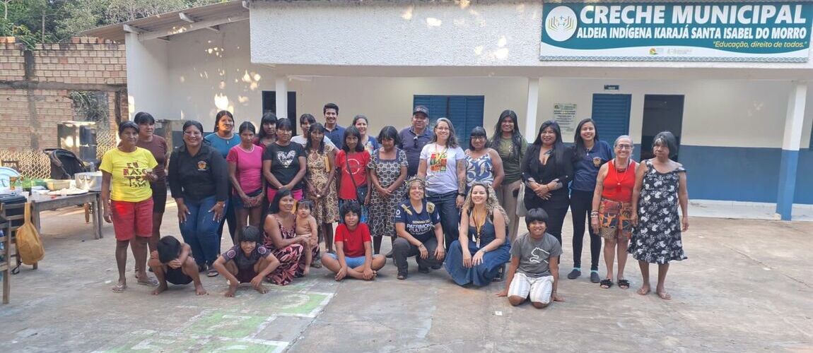 Grupo de pessoas indigenas e equipe técnica do Ipahn em frente a creche municipal da aldeia indígena Karajá