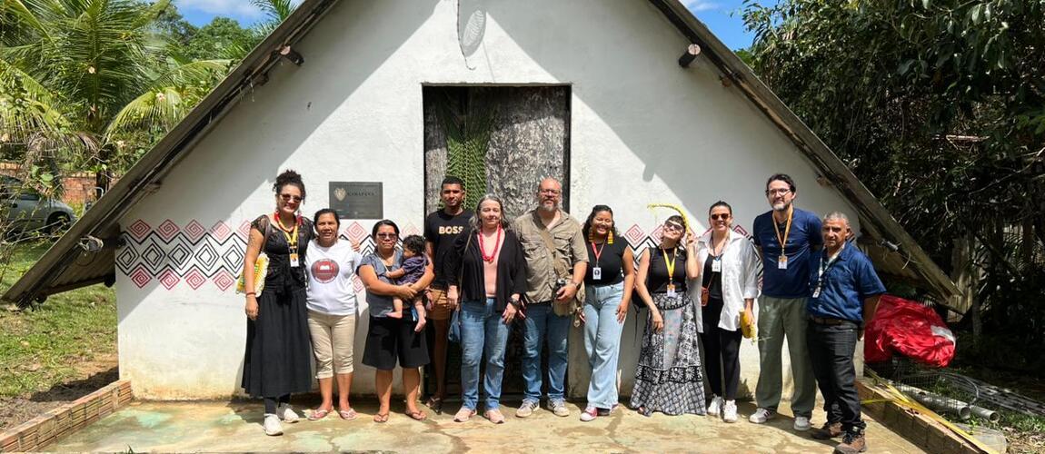 Equipe técnica do Iphan com grupo de pessoas em frente ao museu vivo em Karapãna