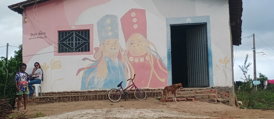 Duas pessoas e um cachorro em frente a uma casa